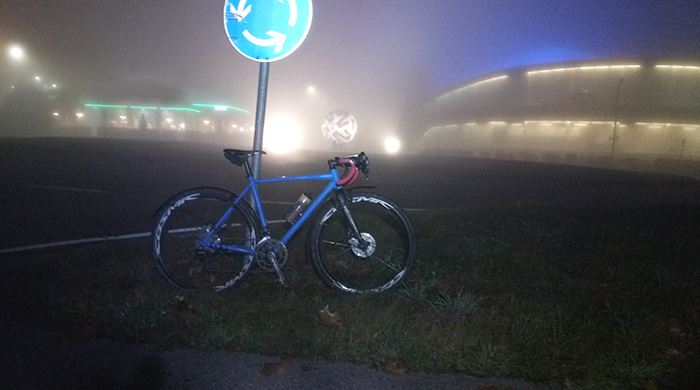 herzobase_blaues_gravelbike_am_kreisverkehr_nachts_im_nebel